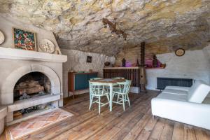 a living room with a fireplace and a table and chairs at Maison semi-troglo - Proche Chenonceaux - Amboise - La Caburoche de Charlemagne in Civray-de-Touraine