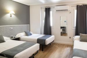 a hotel room with two beds and a window at Alda Centro Palencia in Palencia