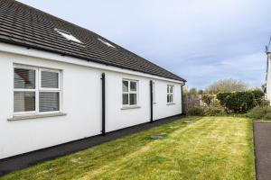 a white house with windows and a yard at Copperbeech Farm Guest House in Moira