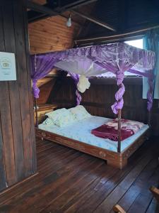 a bed with a canopy in a wooden room at Hotel Anjara in Ambositra