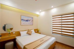 a small bedroom with a bed and a window at Amelia Sầm Sơn Boutique Holtel in Sầm Sơn