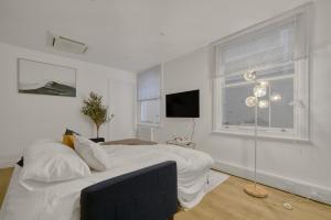 a white bedroom with a bed and a window at The Cozy Quarter in Bromley