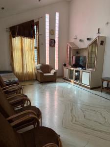 a living room with chairs and a couch and a television at Serenity Villa in Mysore