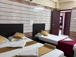 two beds in a room with wooden walls at Hotel Yamunna Boarding and Lodgeing in Kollūru