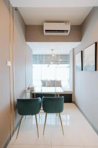 a dining room with a table and two green chairs at Amalea at Benson Pakuwon Mall in Surabaya