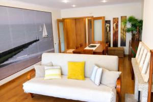 a living room with a white couch with yellow pillows at Oporto Beach Apartment in Vila Nova de Gaia