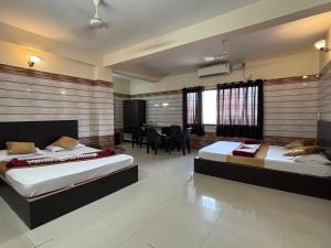 a bedroom with two beds and a dining room at Hotel Yamunna Boarding and Lodgeing in Kollūru