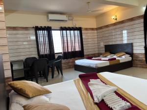 a bedroom with two beds and a desk and a table at Hotel Yamunna Boarding and Lodgeing in Kollūru +8 photos