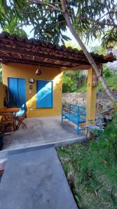 a patio with a blue bench in front of a house at Chalé Almar - Praia do Sagi in Baía Formosa