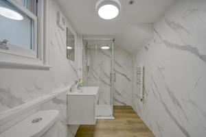a white bathroom with a sink and a mirror at The Cozy Quarter in Bromley