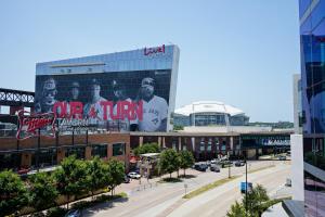 a large building with a billboard with the beatles on it at Live! by Loews - Arlington, TX in Arlington