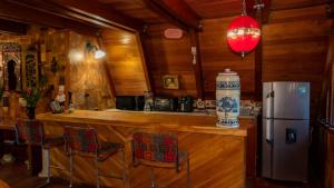 a kitchen with a bar with chairs and a refrigerator at cabaña master familiar in San Antonio de Pereira +10 photos