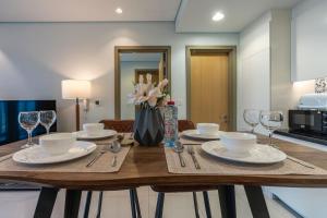 a wooden table with plates and glasses and a vase of flowers at Near Dubai Mall PoolAccess SunSetView KingBed in Dubai +30 photos