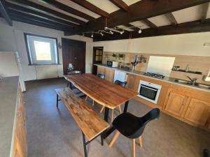 a large kitchen with a wooden table and chairs at La P'tite Chaumiere in Domaize