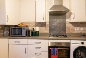 a kitchen with white cabinets and a stove top oven at Quiet Three-Bedroom Home in Stewartby with Ensuite and Workspace in Bedford