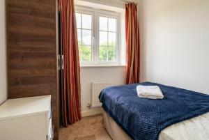 a bedroom with a blue bed and a window at Quiet Three-Bedroom Home in Stewartby with Ensuite and Workspace in Bedford
