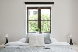 a white bedroom with a bed with a window at Linneby in Uddevalla