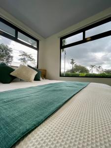 a bedroom with a green rug on a bed with large windows at Casa Eucalipto in Chachagua