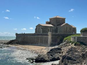 an old church on a cliff next to the ocean at Charmante maison vue chenal in Les Sables-d'Olonne