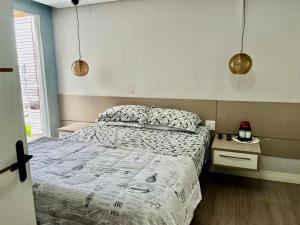 a bedroom with a bed and two pendant lights at Mello's House in Curitiba