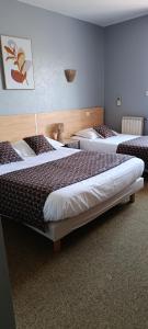 a room with three beds in a room at Hôtel Le Relais in Fleurance