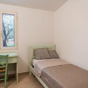 a bedroom with a bed and a desk and a window at Domo Appeddu in Orosei
