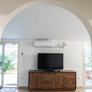 a flat screen tv sitting on top of a wooden entertainment center at Domo Appeddu in Orosei