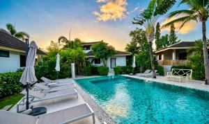 a swimming pool with chairs and umbrellas in front of a house at Tulum Villa Resort Koh Samui in Bophut