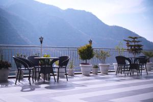 a group of chairs and tables on a balcony with mountains at Bell Mount Mussoorie Hill view Hotel in Mussoorie