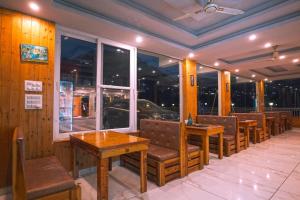 a restaurant with benches and tables and windows at Bell Mount Mussoorie Hill view Hotel in Mussoorie