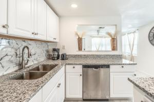 a kitchen with white cabinets and a stainless steel dishwasher at Noel Real Estate in Naples +34 photos