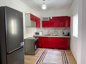 a kitchen with red cabinets and a stainless steel refrigerator at Guesthouse Camping the peaceful of Koman in Gushtë