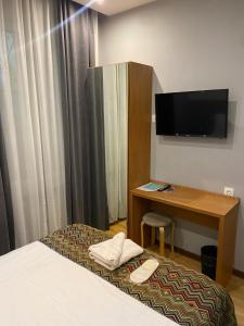 a hotel room with a bed and a desk and a television at Downtown Hotel in Tbilisi City