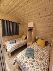 two beds in a room with wooden walls at Le Clos des Chenevières in Rainville