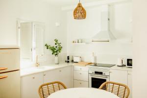 a kitchen with white cabinets and a table and chairs at Casa do Mar - Casas do Levante in Olhão +28 photos