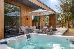 a bath tub with chairs and umbrellas on a deck at Feriehus 1161 in Ringkøbing