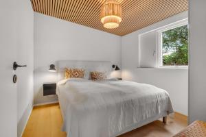 a white bedroom with a bed and a window at Feriehus 1161 in Ringkøbing