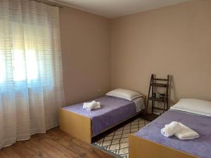 a bedroom with two beds and a window with curtains at Kuća za odmor - Snowwhite in Smoković