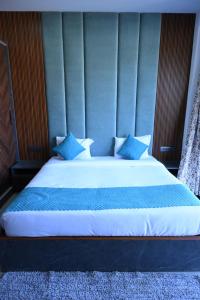 a bed with a blue headboard with blue pillows at THE BBN Hotel in Solan