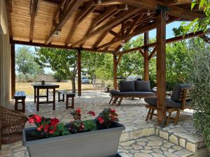 a patio with a wooden pergola with furniture and flowers at Kuća za odmor - Snowwhite in Smoković