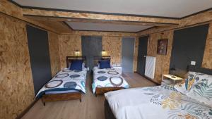 two beds in a room with wooden walls at Chambre d'hôtes MA DAME in Clérey