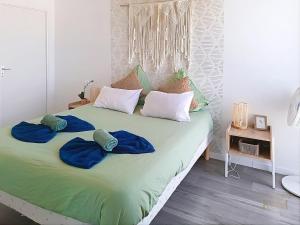 a bed with two blue pillows on top of it at L'Échappée Verte - T2 avec balcon in Saulx-les-Chartreux