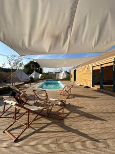 two lounge chairs and a pool under a large umbrella at Amurg Glamping&Pool in Vadu