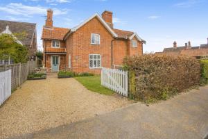 a brick house with a white fence in front of it at 3 Bed in Dunwich oc-slh in Dunwich