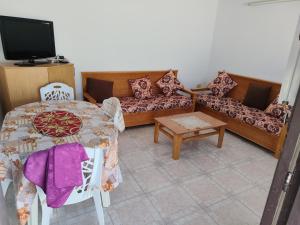 a living room with a table and a couch at Studio ANDALOUS in Mahdia
