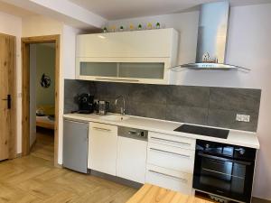 a kitchen with white cabinets and a sink and a stove at Apartamenty JENDRYCÓWKA in Korbielów