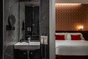 a bathroom with a sink and a bed with red pillows at BYPILLOW Callao in Madrid +93 photos