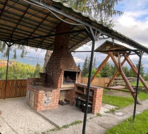 an outdoor pizza oven with a roof on a patio at котедж Квітуча Гора in Yablunytsya