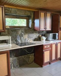 a kitchen with wooden cabinets and a stone wall at котедж Квітуча Гора in Yablunytsya