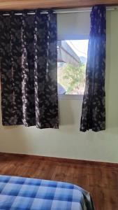 a bedroom with a window with black curtains at Cabana in Santo Antônio do Pinhal